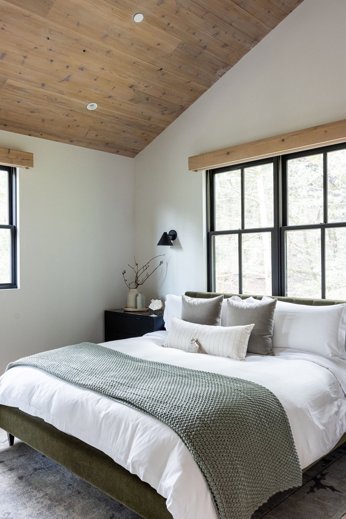 Bedroom with large black-framed windows and natural textures
