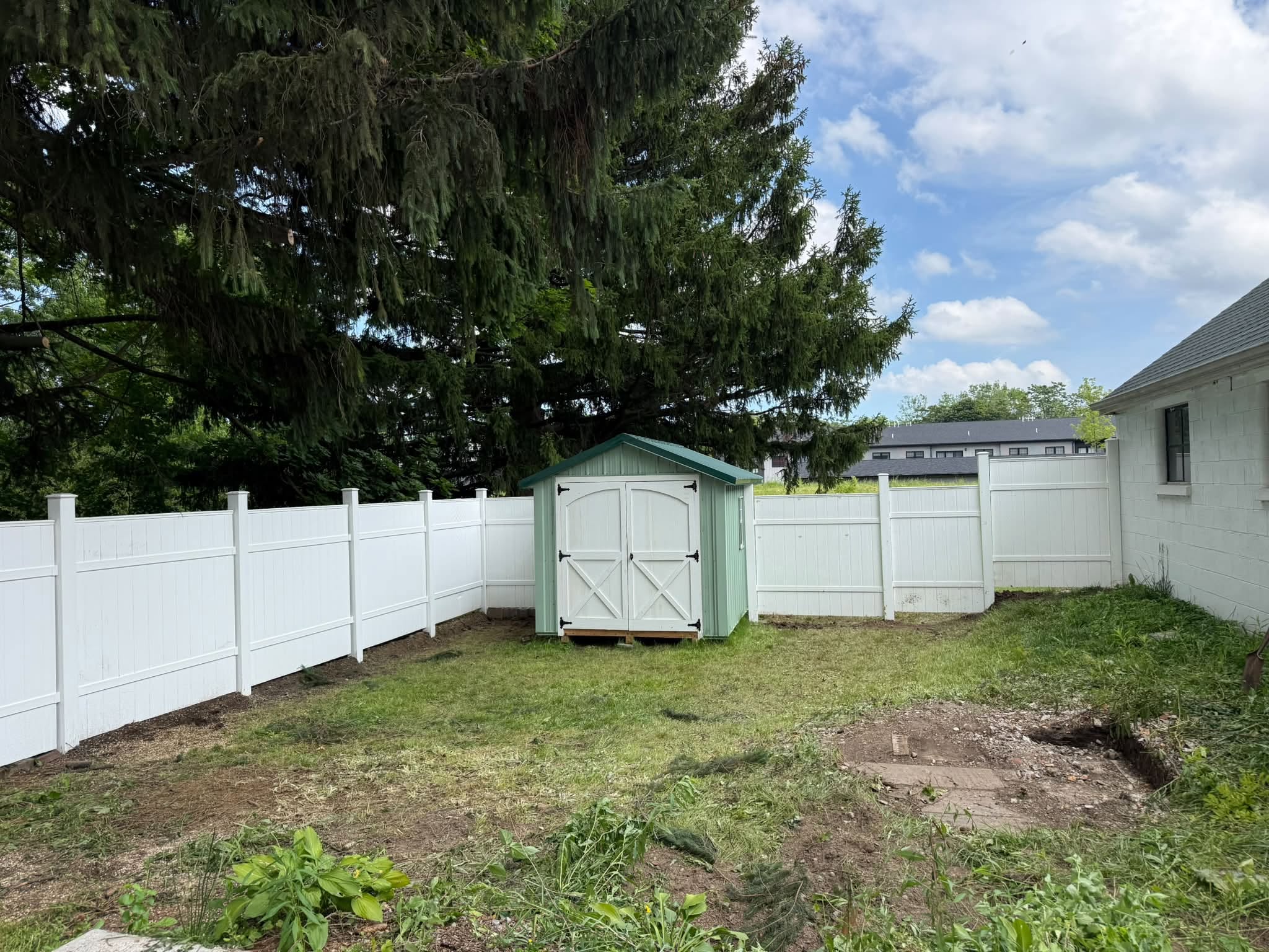 White vinyl privacy fence and garden shed in a backyard